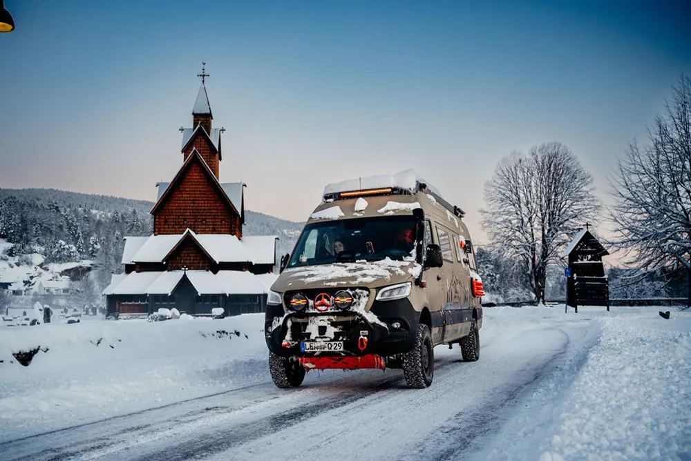 Der Sprinter vor einer verschneiten Stabkirche